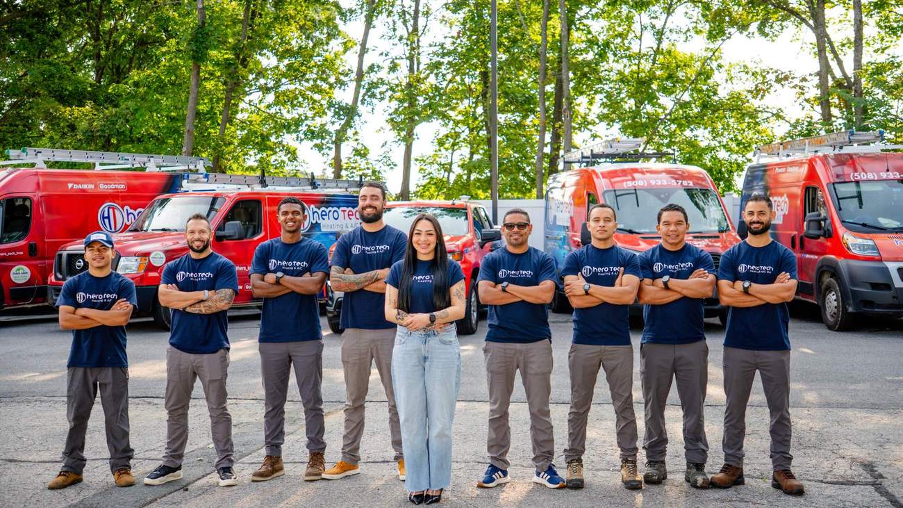 The Hero Tech Heating & A/C crew in uniform in front of the company service vans in Marlborough, Massachusetts