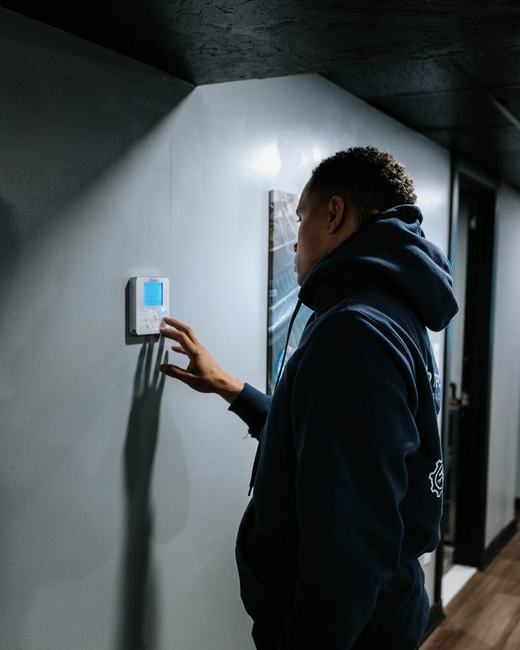 A Hero Tech technician setting a thermostat after a heat pump installation