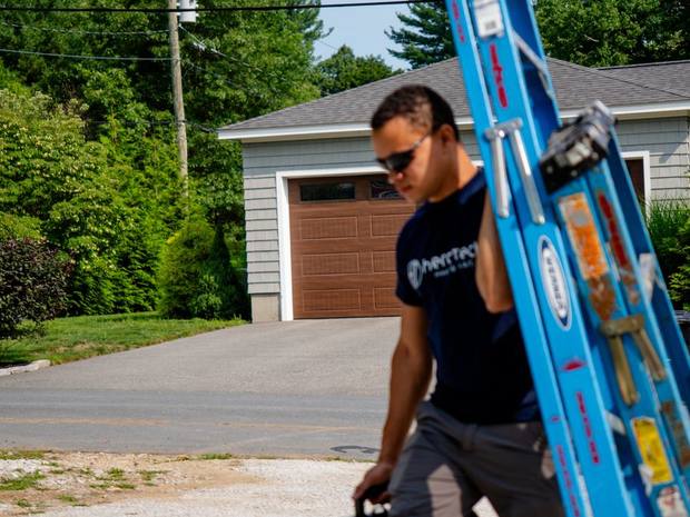 A Hero Tech technician arriving at a home with a ladder and tool case for a maintenance visit