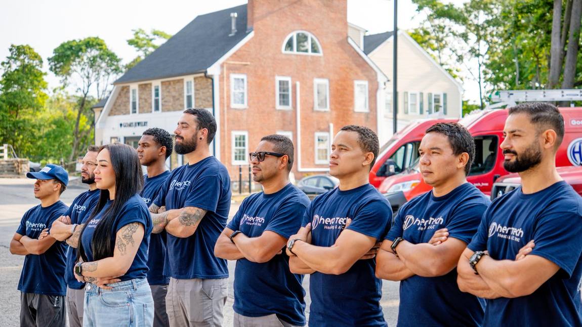 The Hero Tech Heating & A/C crew in uniform in front of the company service vans in Marlborough, Massachusetts